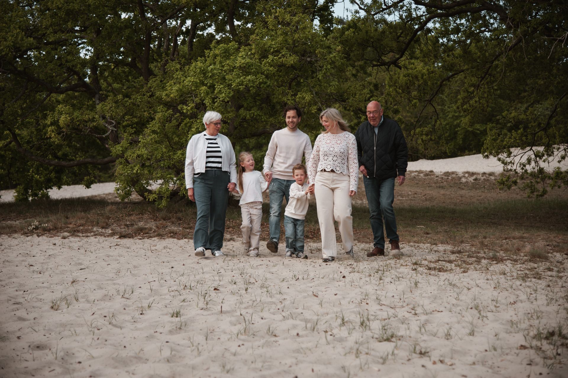 Een familie wandelt samen door de duinen.