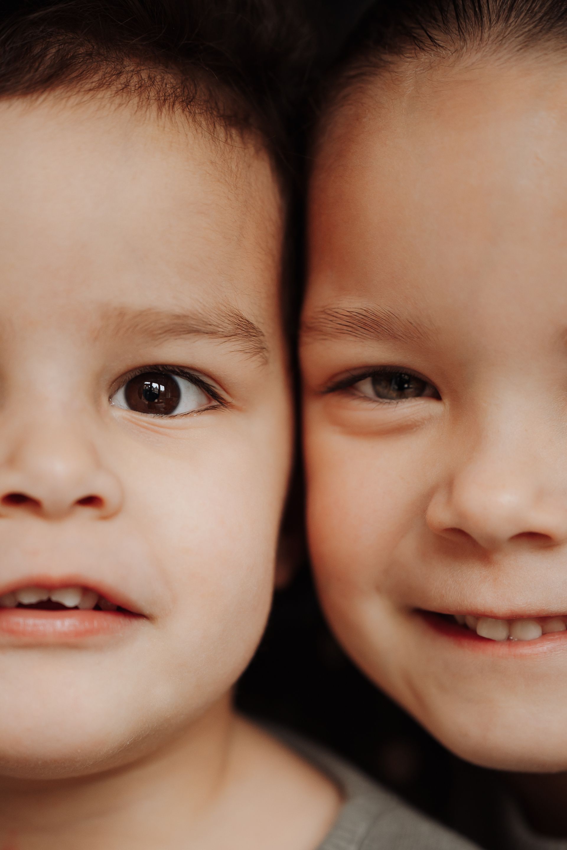 Een vrouw houdt een kind vast in een bos. Het kind, met blond haar, kijkt over haar schouder en glimlacht.
