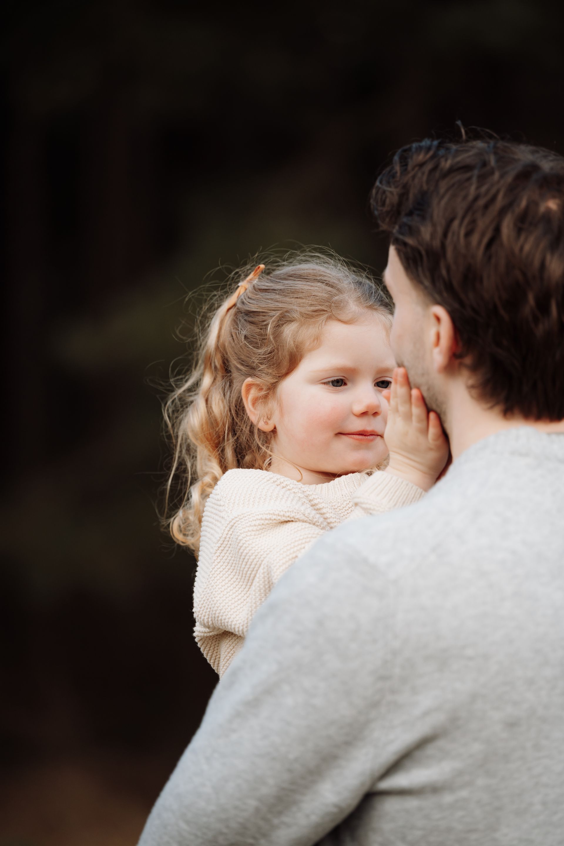 Een lachende baby zit op de schoot van een vrouw in een veld met paarse bloemen.