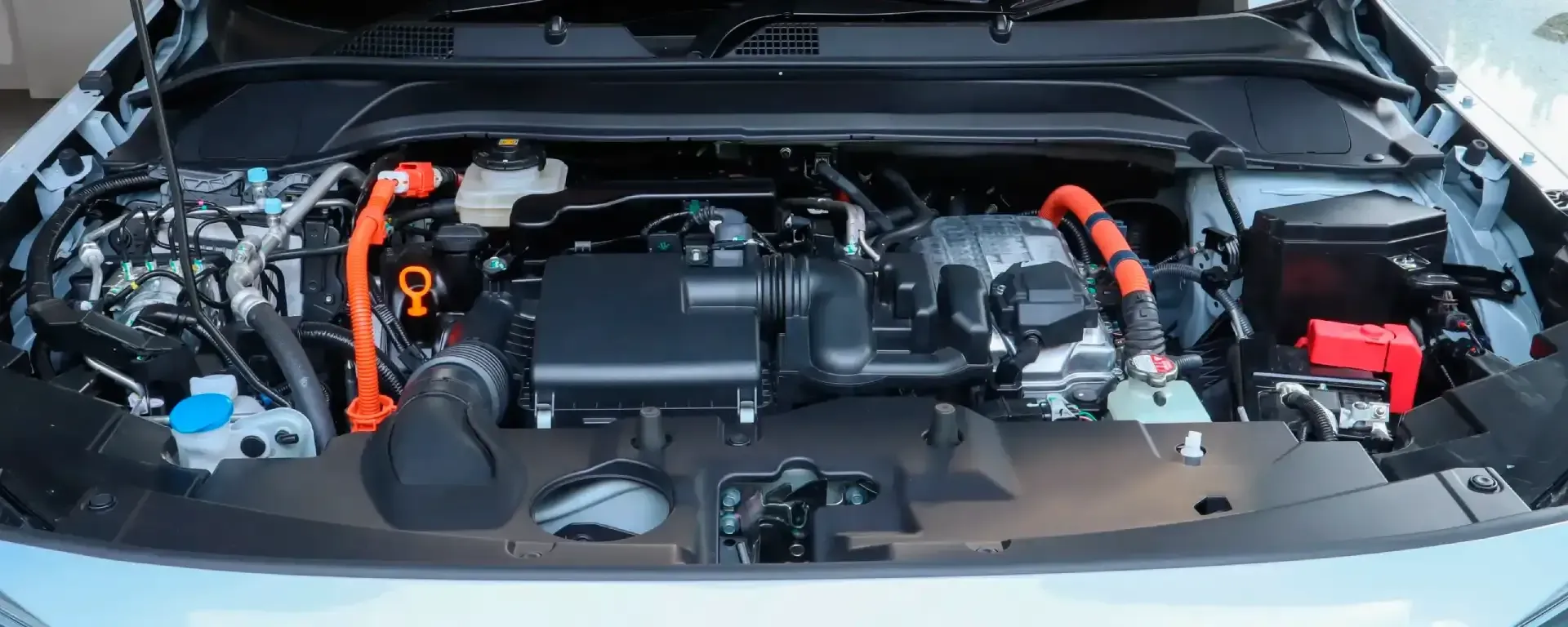 Open car engine bay with visible components and orange fluid caps