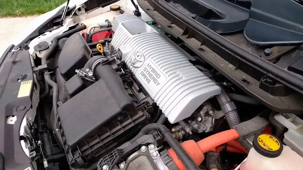 Car engine bay with silver intake cover, black components, and orange battery cable.