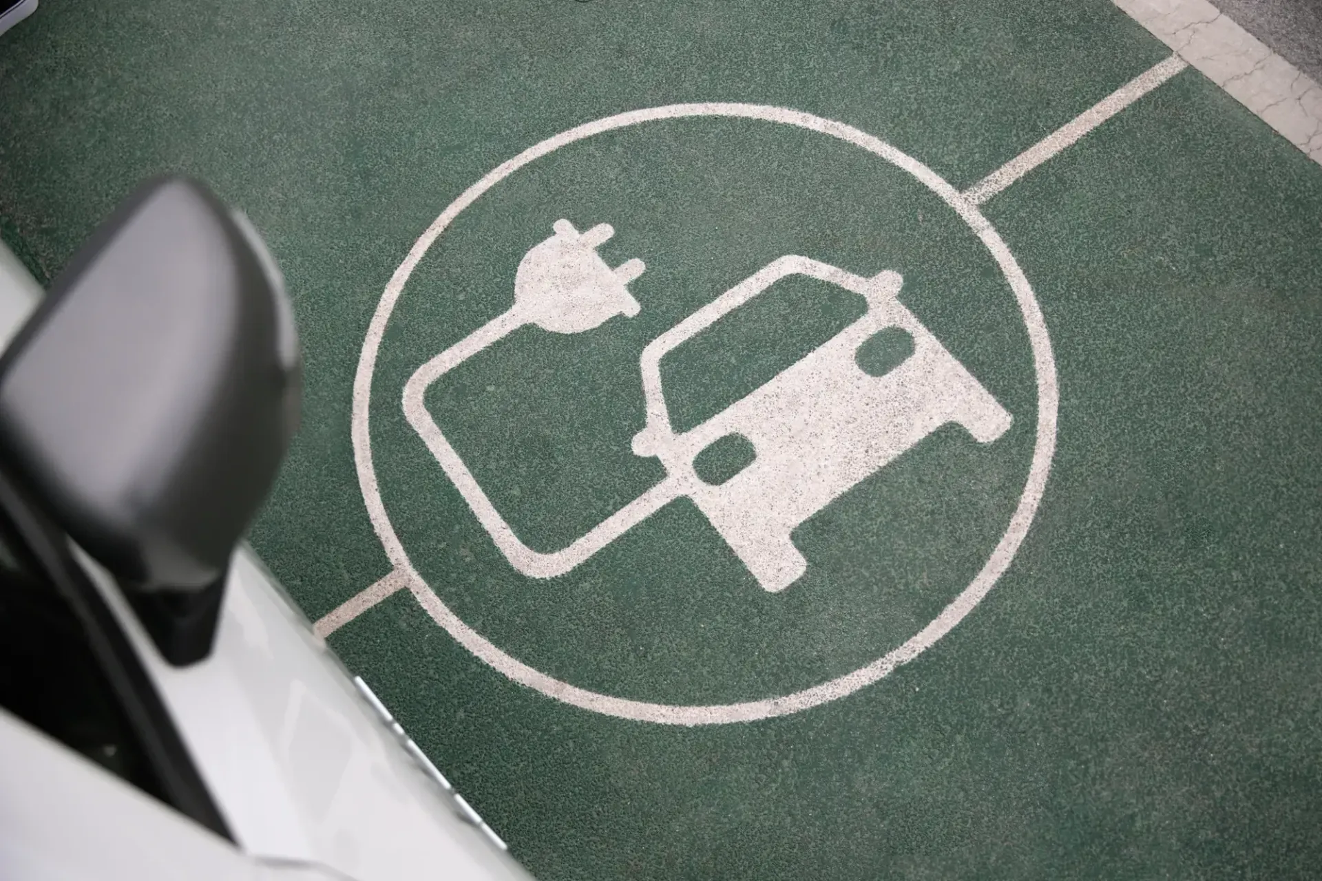 Green painted EV charging parking space with a plug and car symbol, viewed from above