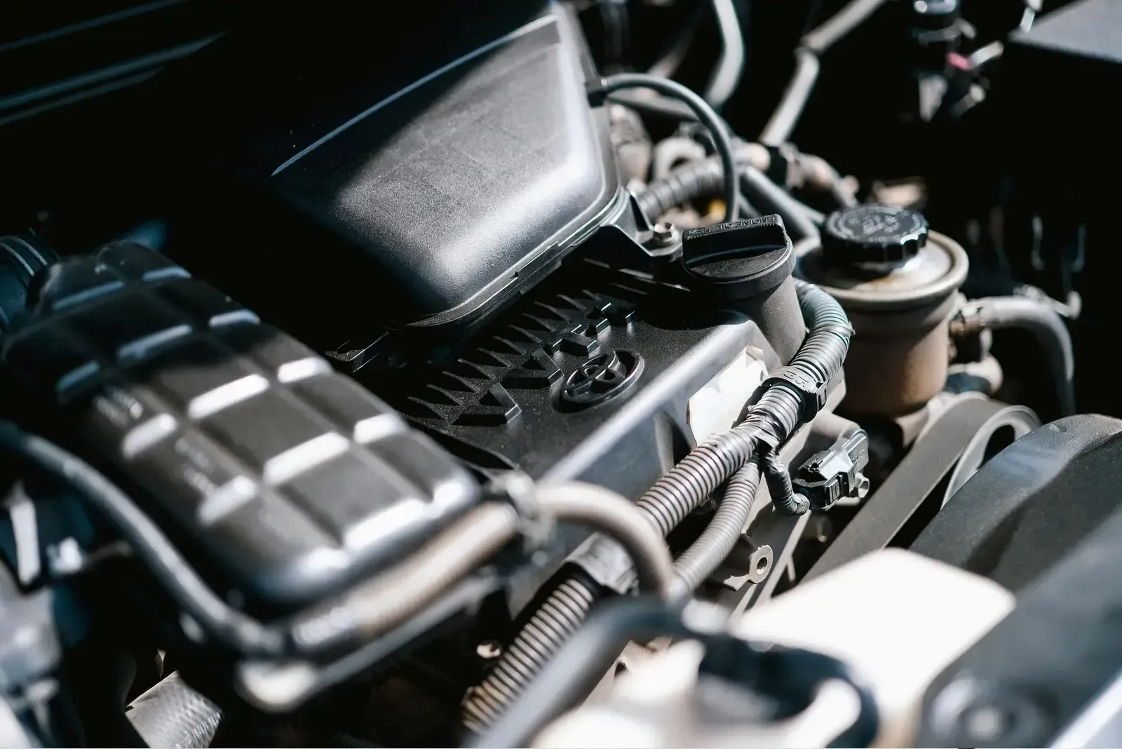 Close-up of a car engine bay with black components and metal parts