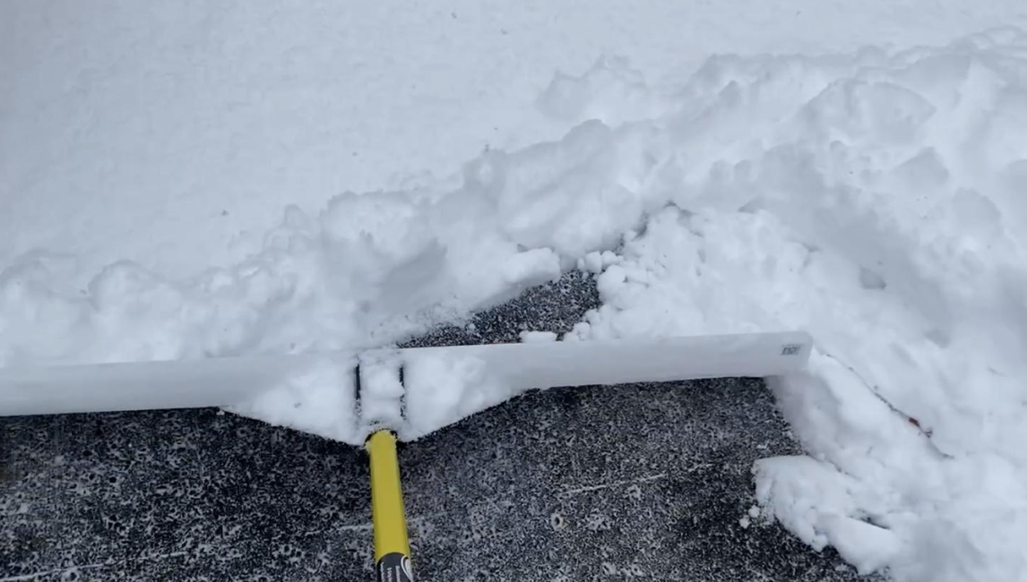 A shovel is being used to remove snow from the ground.