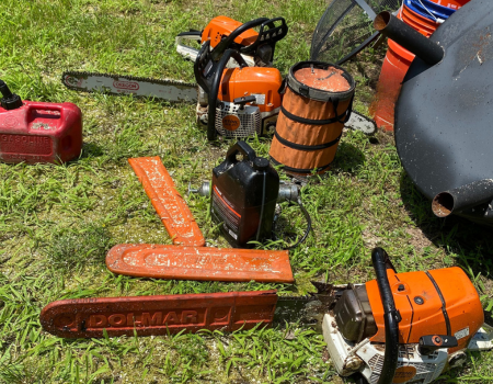 a stihl chainsaw is laying on the grass next to a gasoline can