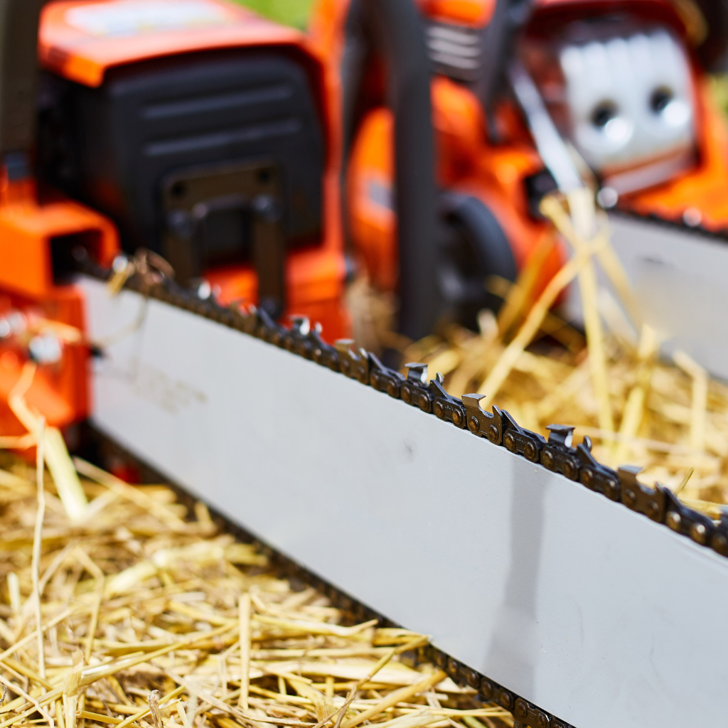 two gas chainsaws on some hay