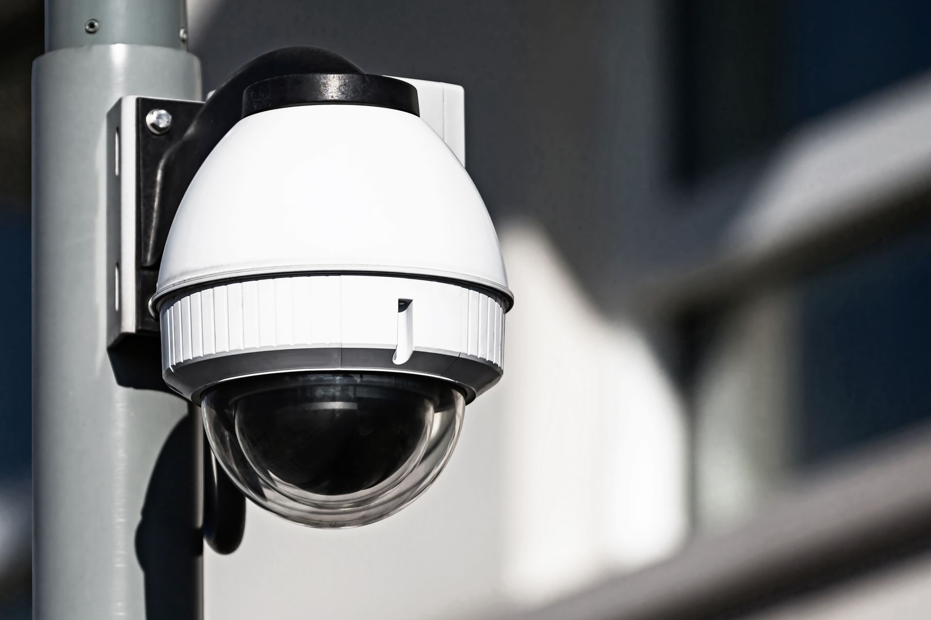 A security camera is mounted on a pole outside of a building.