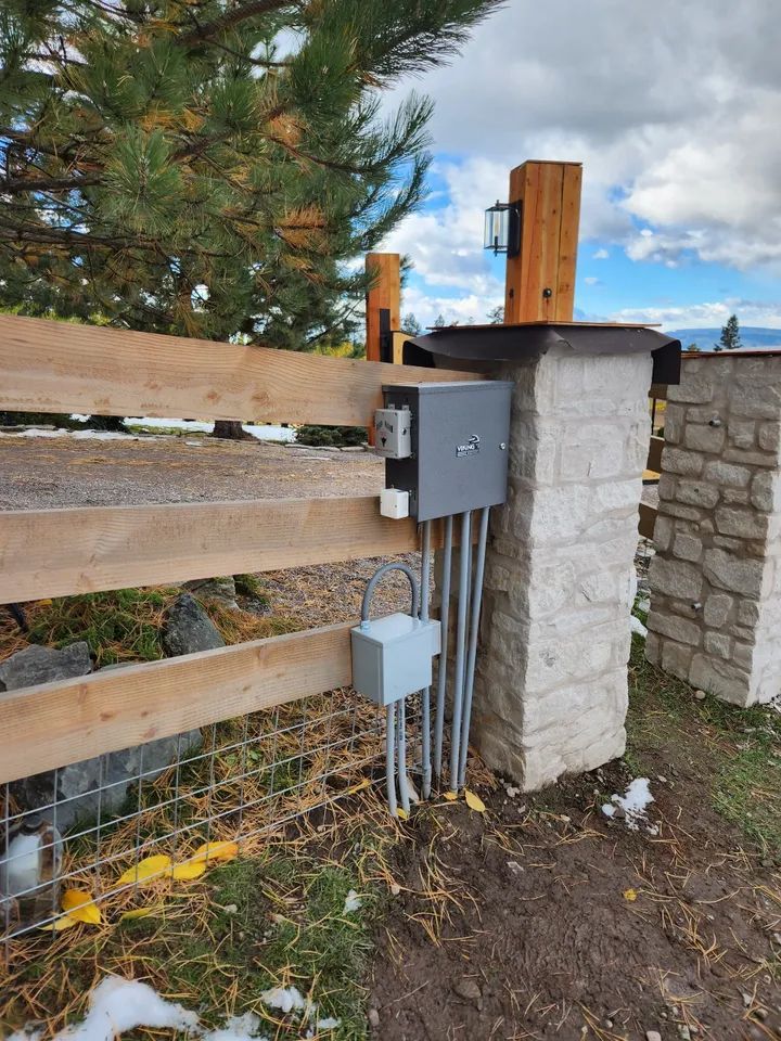 A wooden fence with electrical wires coming out of it.