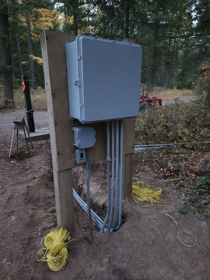 A box is sitting on a wooden post in the dirt.