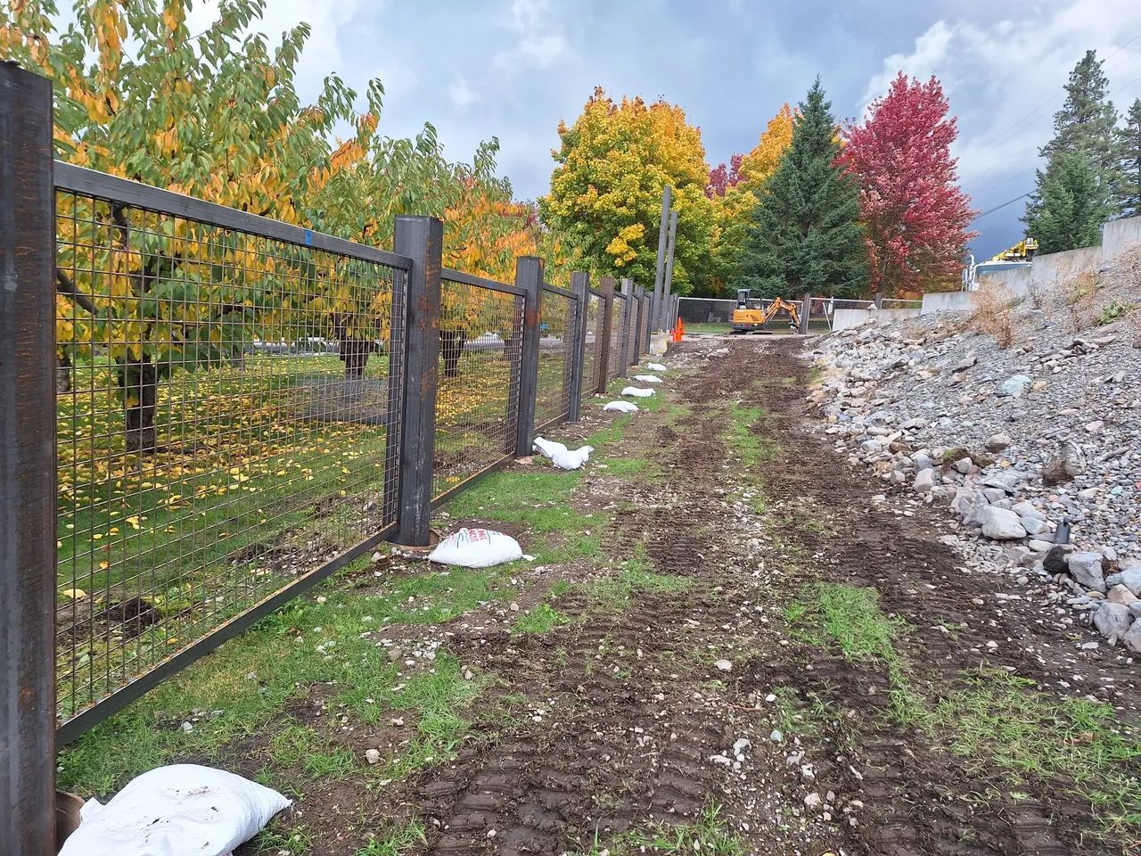 A fence is being built in a field with trees in the background.