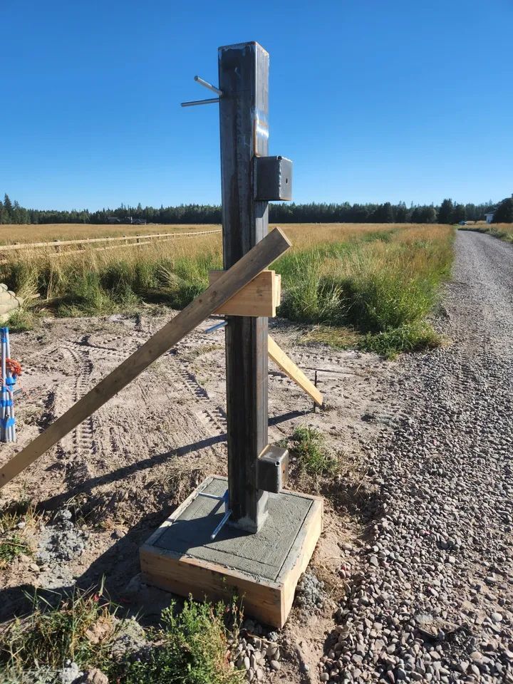 A fence post is sitting on the side of a gravel road.