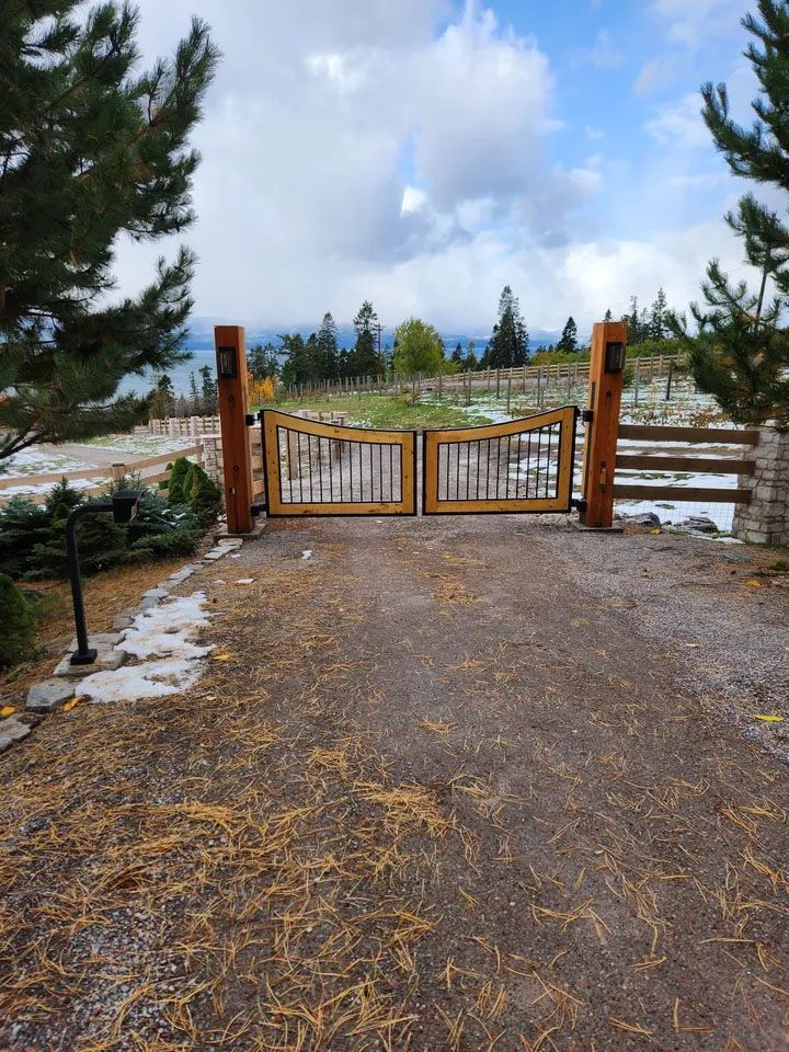 A wooden gate is sitting on the side of a dirt road.