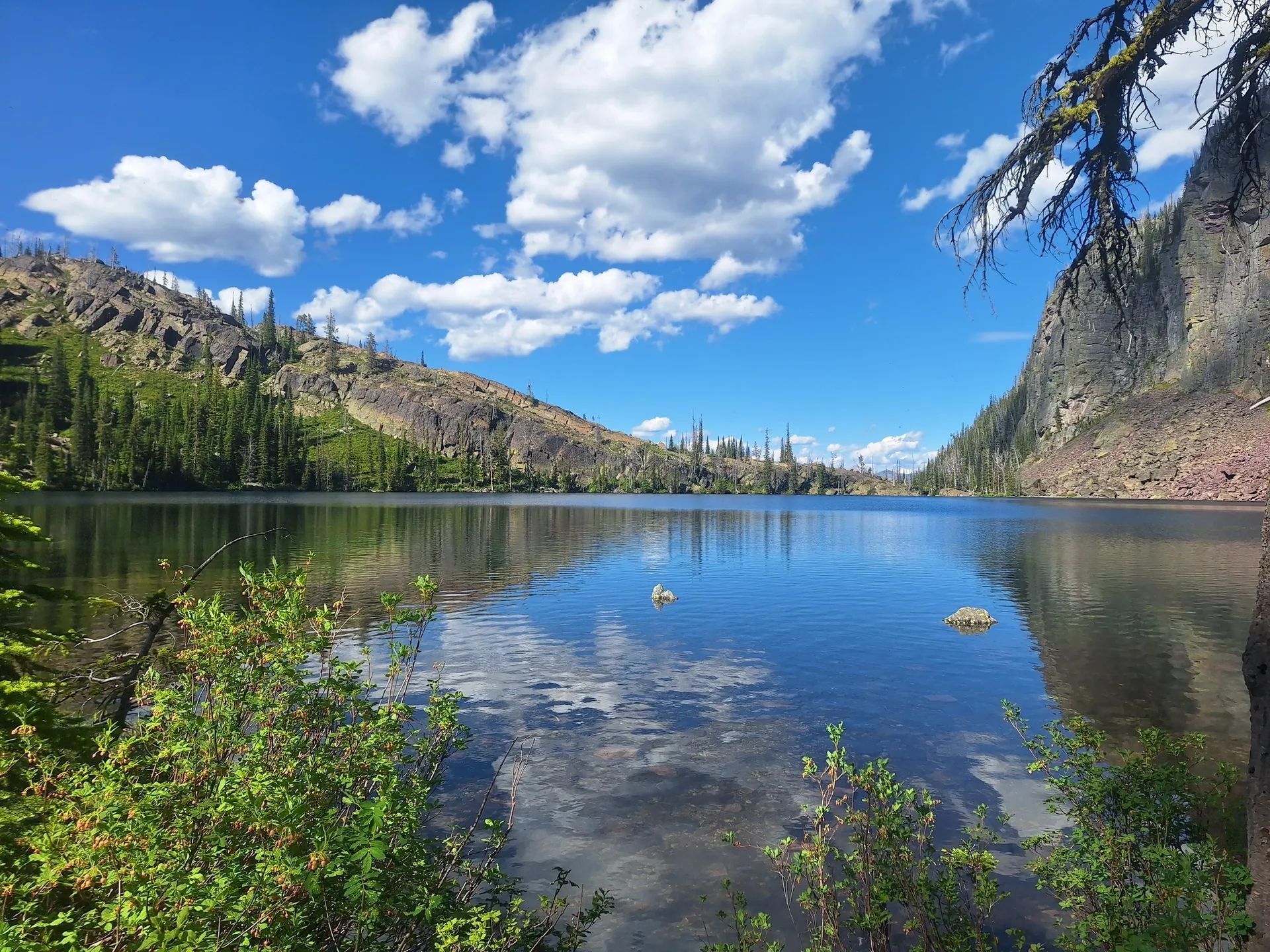 A lake surrounded by mountains and trees on a sunny day