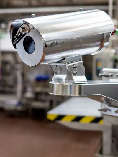 A security camera is sitting on top of a machine in a factory.