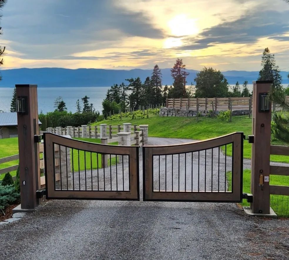 A driveway with a wooden fence and a metal gate