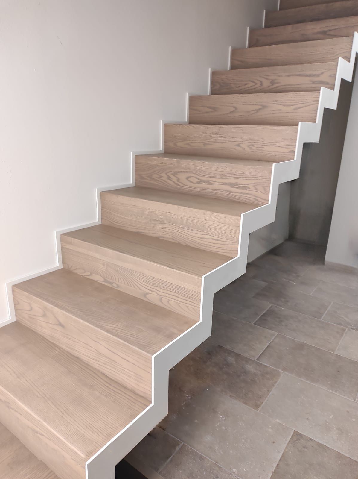 Una scala con gradini in legno e ringhiera bianca.