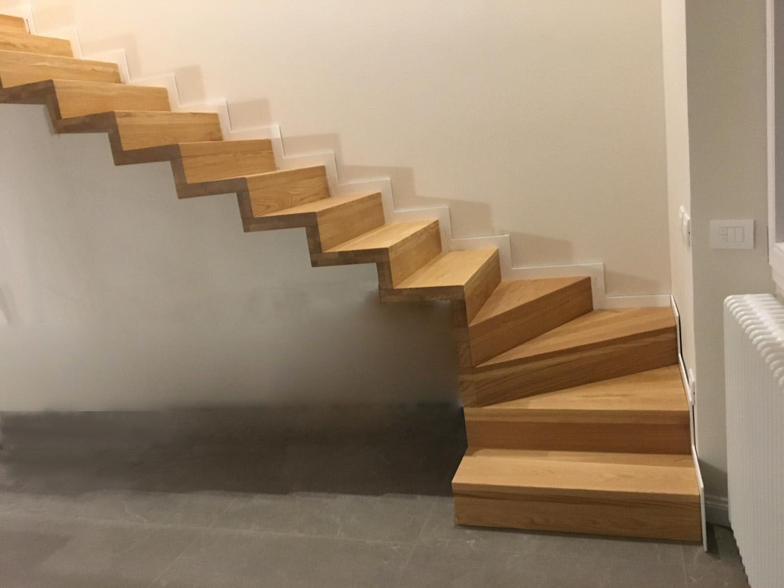 Una scala di legno in una stanza con una parete bianca.