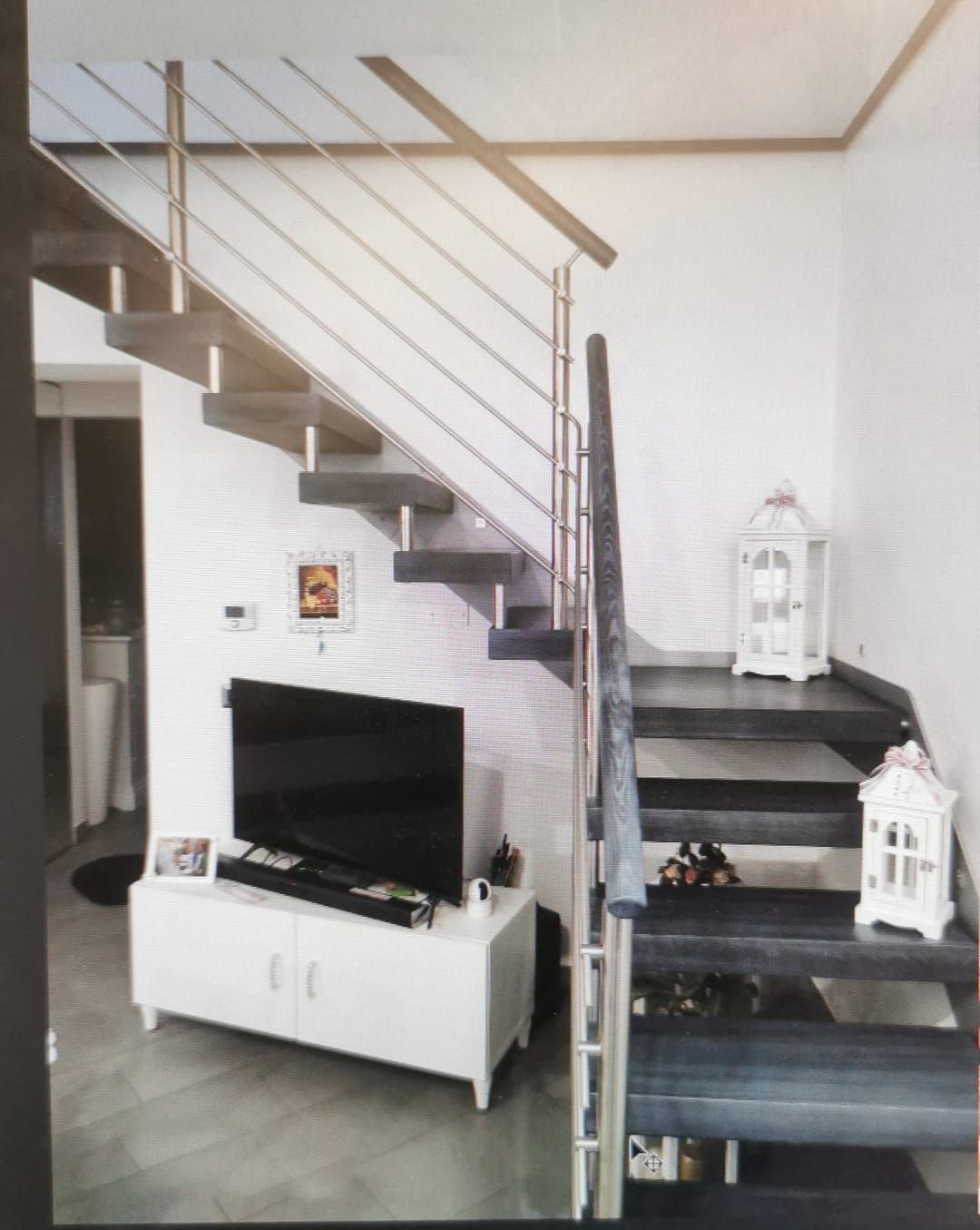 Un soggiorno con scale e una tv a schermo piatto