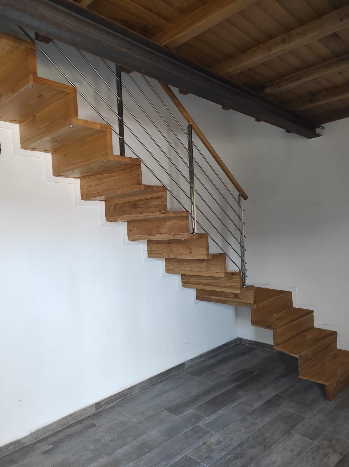 Una scala di legno con ringhiera di metallo in una stanza.