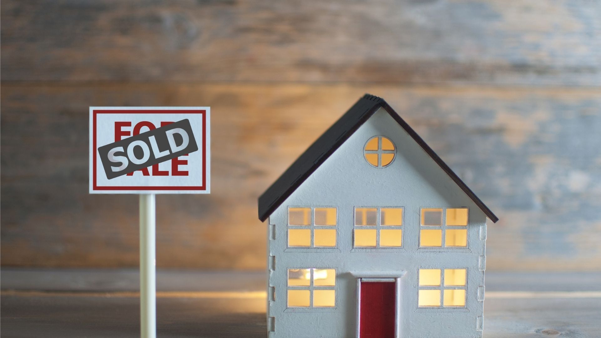 A model house is sitting next to a sold sign.