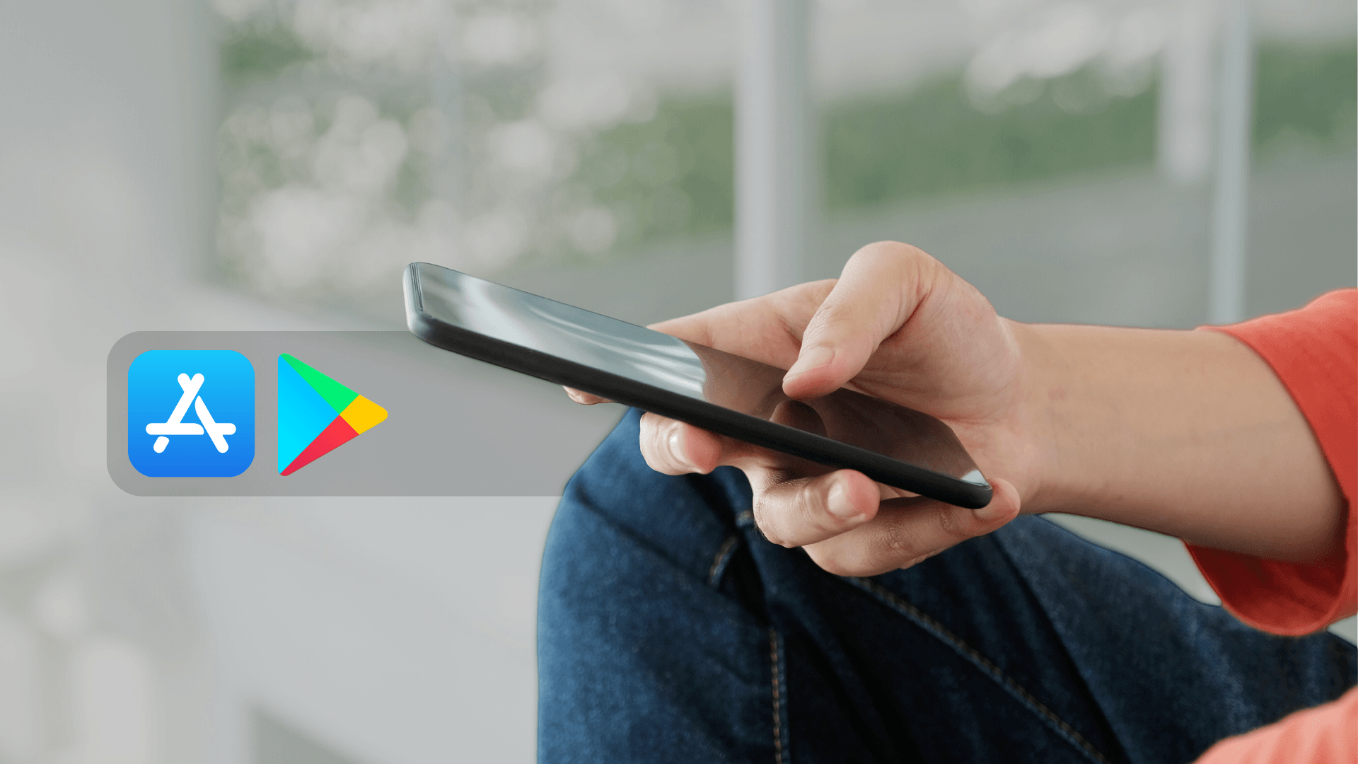 A person is holding a cell phone in their hand in front of an app store icon.