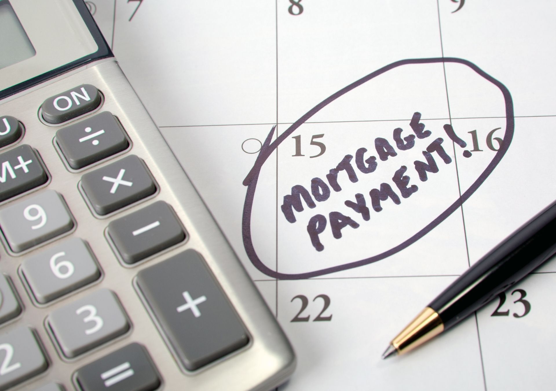 A calendar with a pen and a calculator with the words mortgage payment written on it