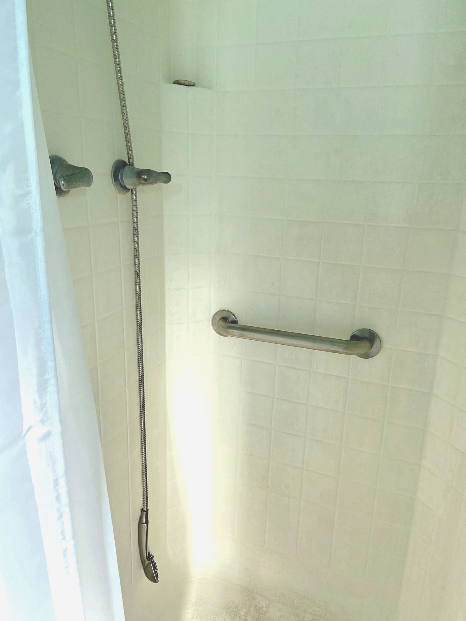 A shower stall with a chain hanging from the wall
