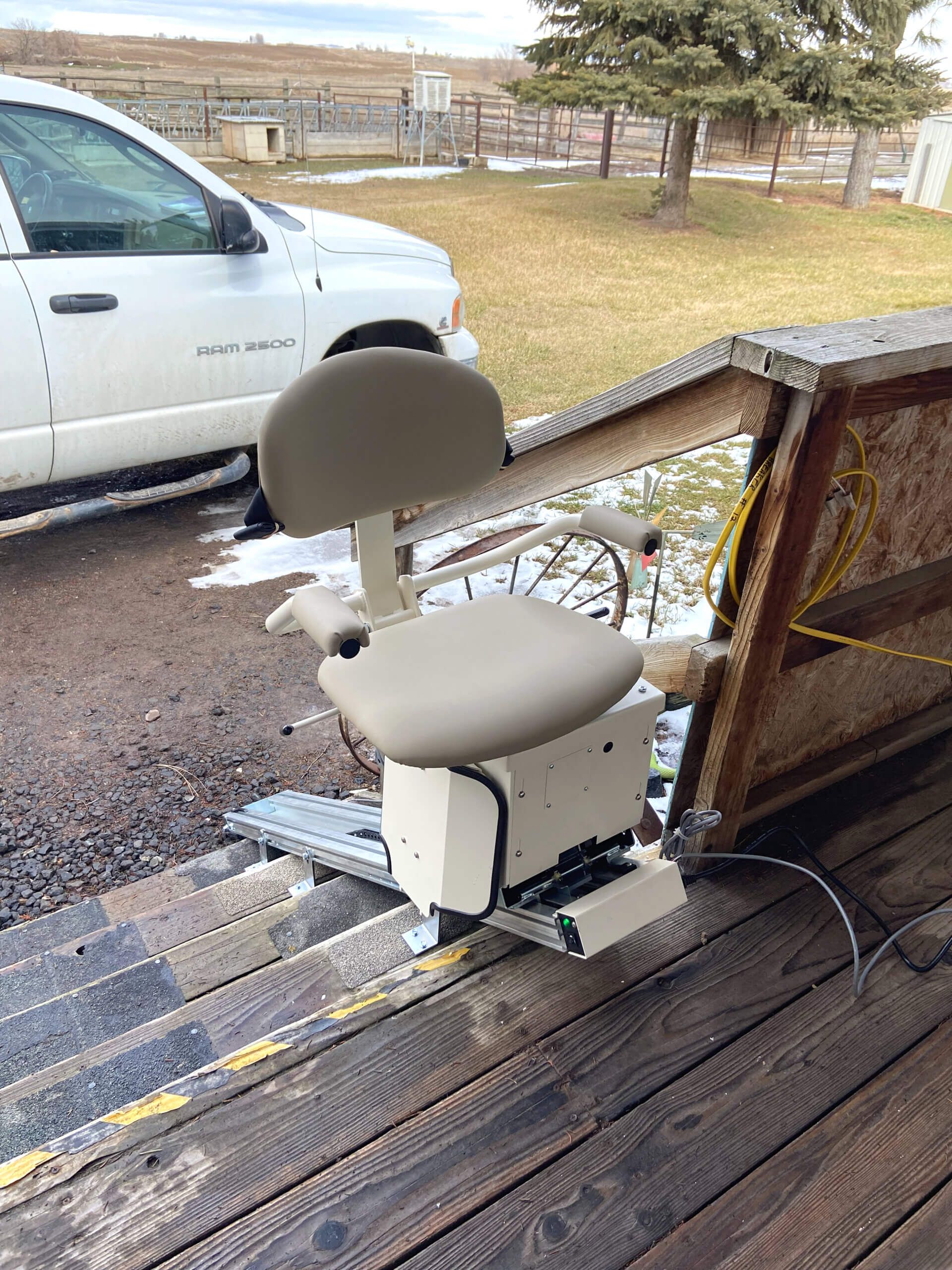 A chair is sitting on a wooden deck next to a white truck.