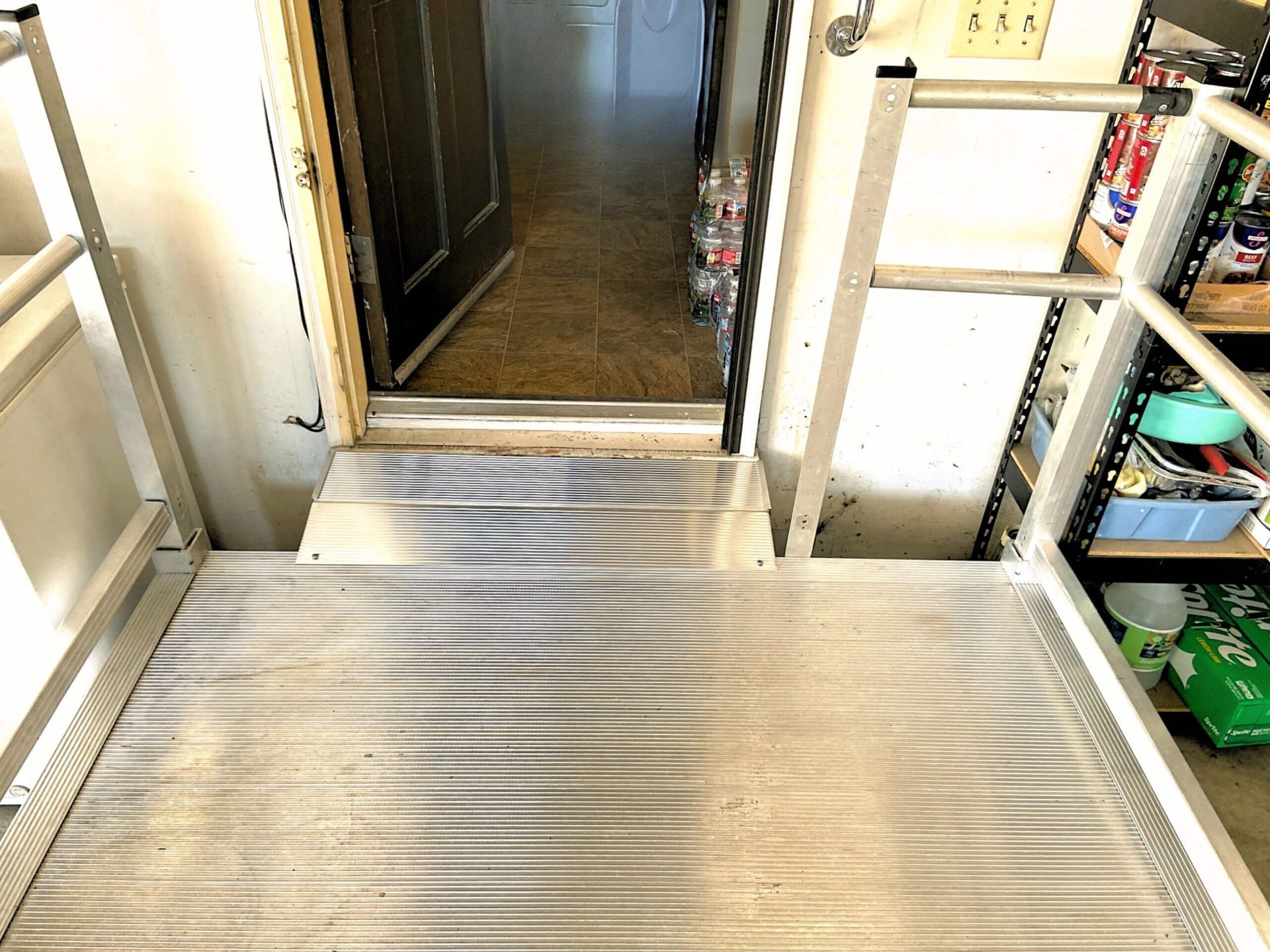 A metal ramp leading to a doorway in a room with a ladder.