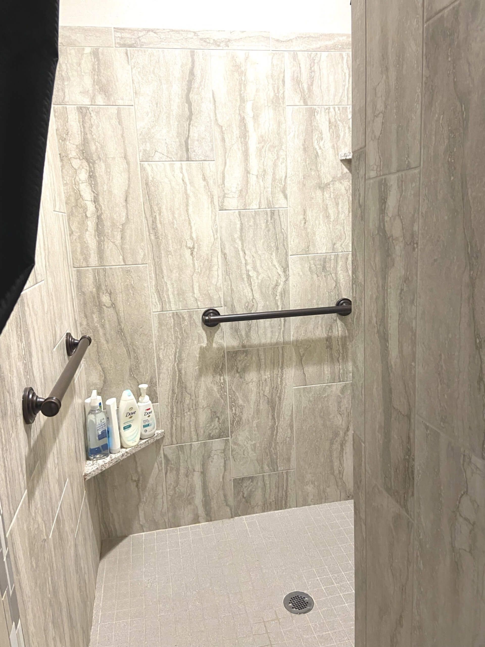 A bathroom with a walk in shower and a shelf with bottles on it.