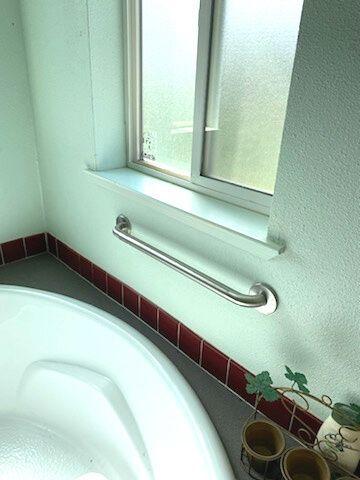 A bathroom with a tub and a window with a handle on the window sill.