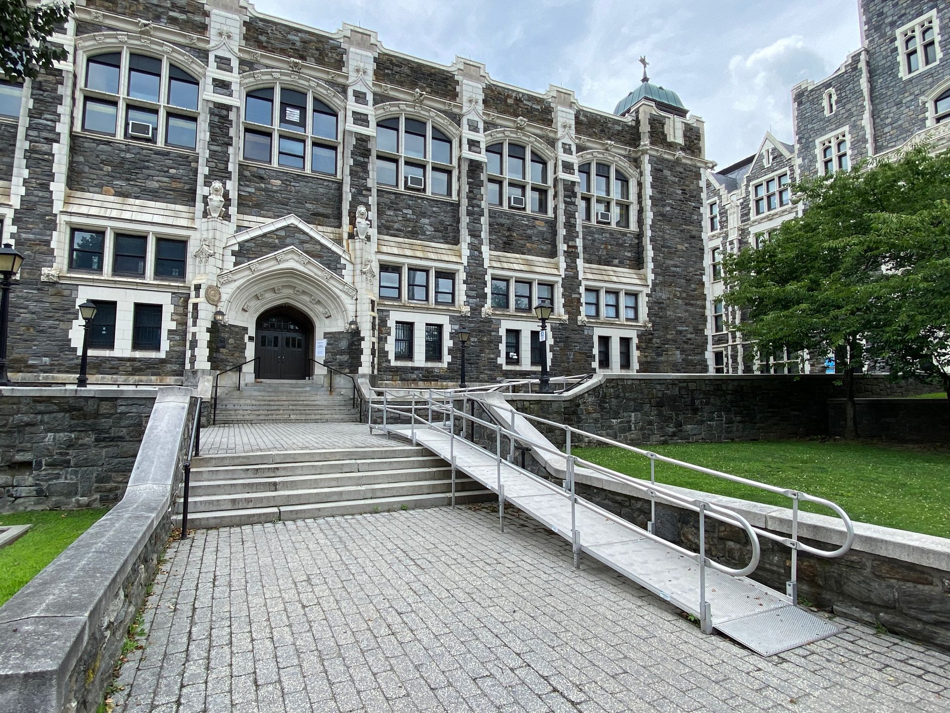 Historic stone building with arched entrance and accessibility ramp.