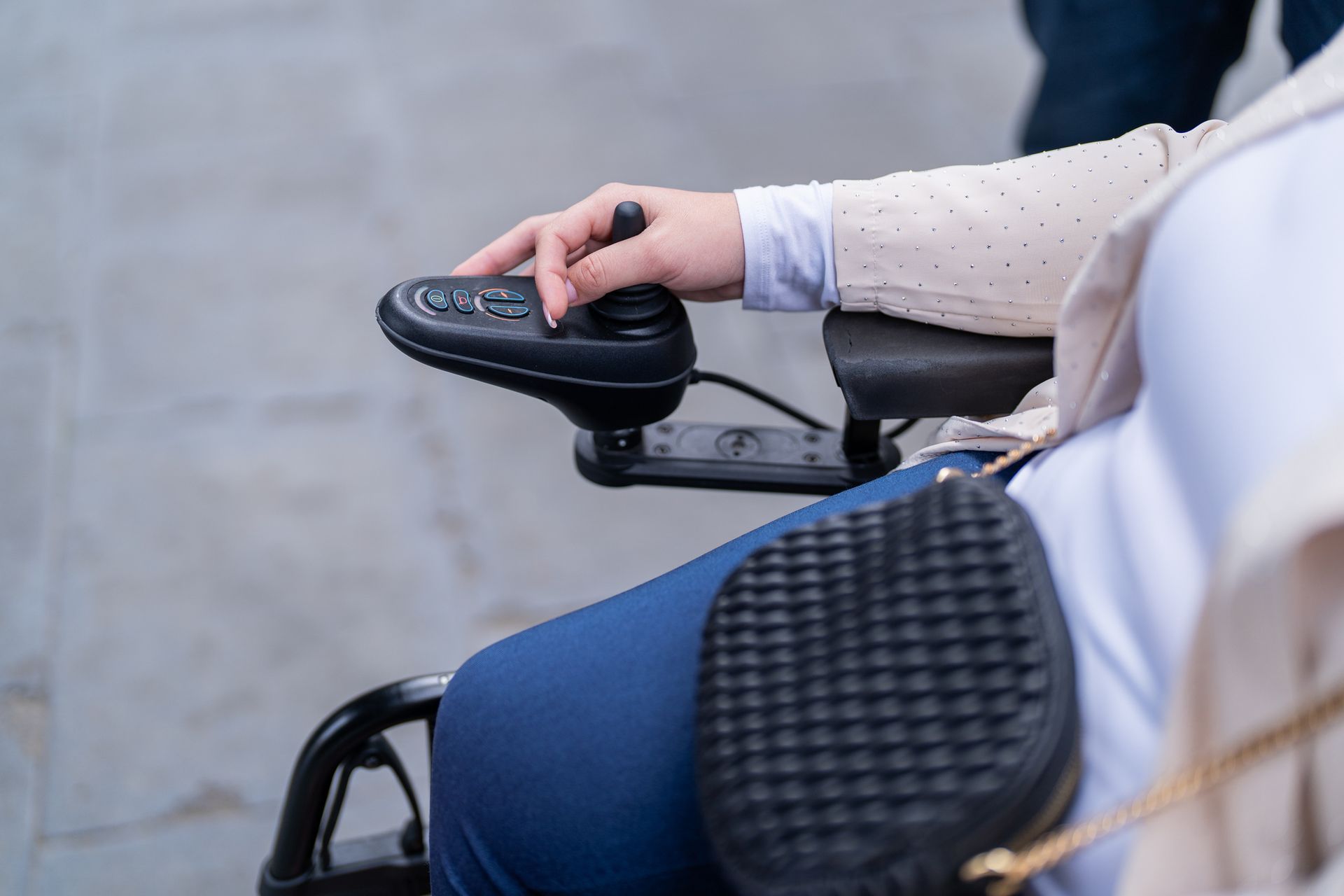 Hand on joystick controlling electric wheelchair.