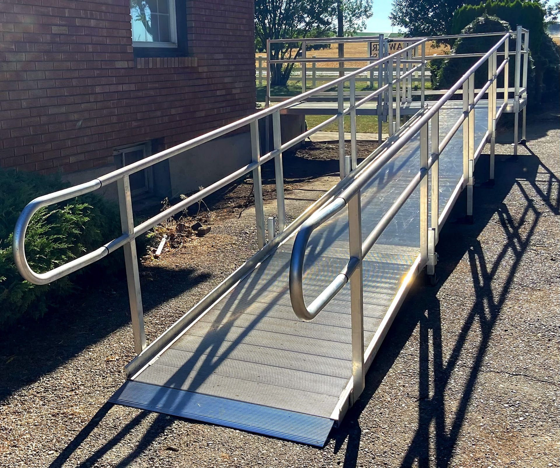 A ramp with a stainless steel railing leading to a brick building