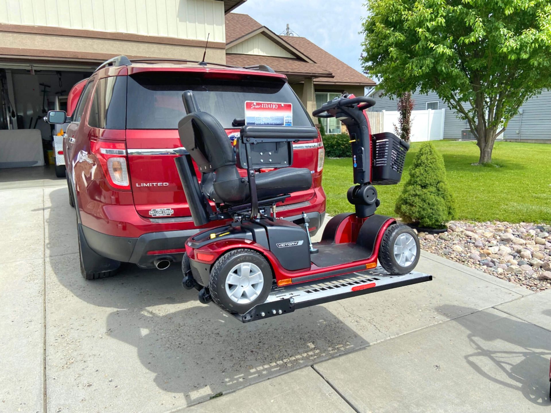 A mobility scooter is attached to the back of a red SUV
