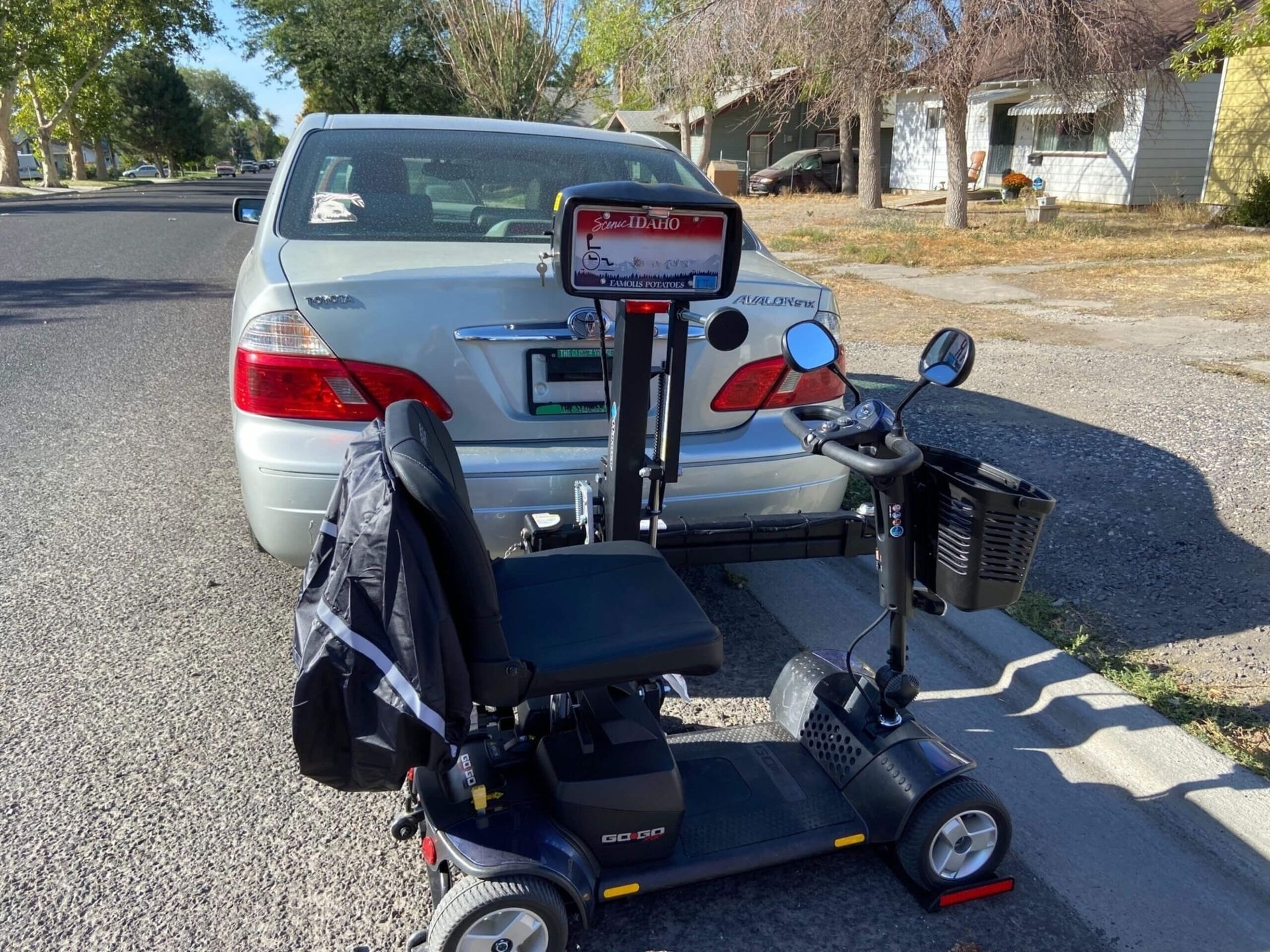 A mobility scooter is parked next to a car on the side of the road.