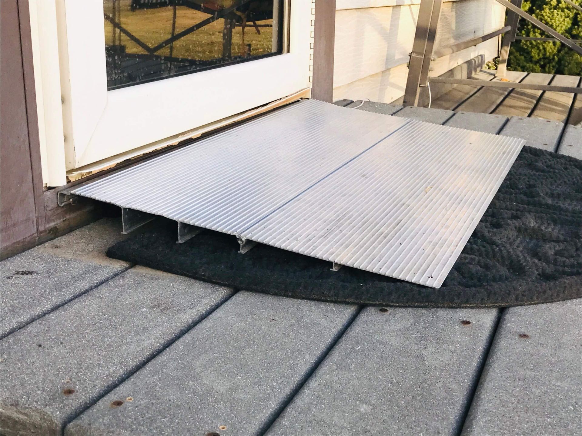 A ramp is sitting on a wooden deck next to a door.