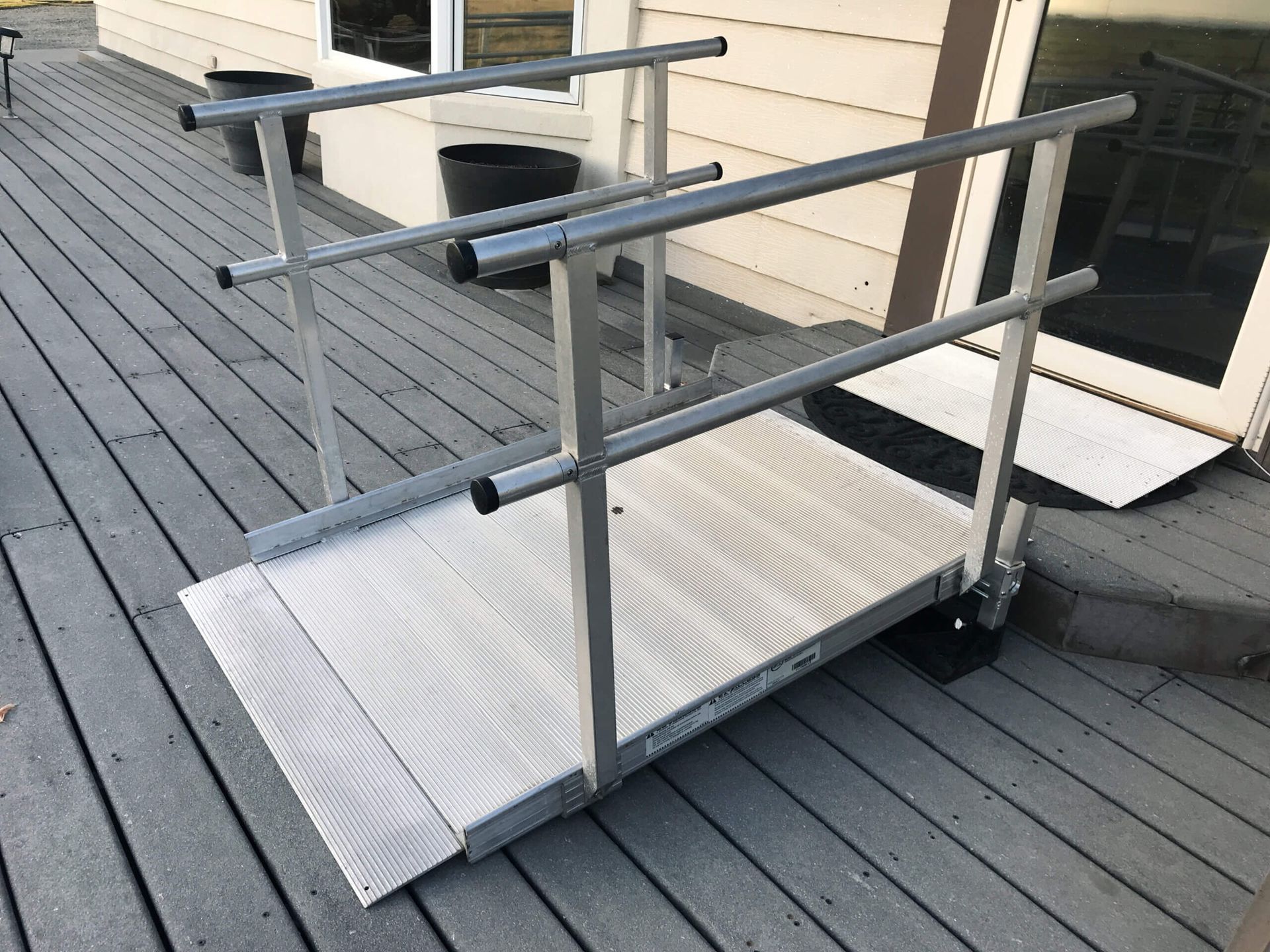 A ramp is sitting on a wooden deck next to a house.