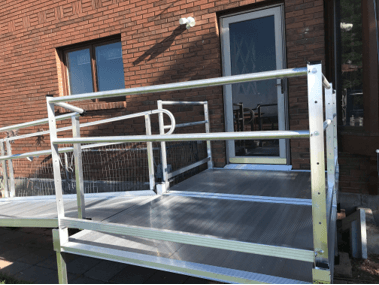A wheelchair ramp is sitting in front of a brick building.