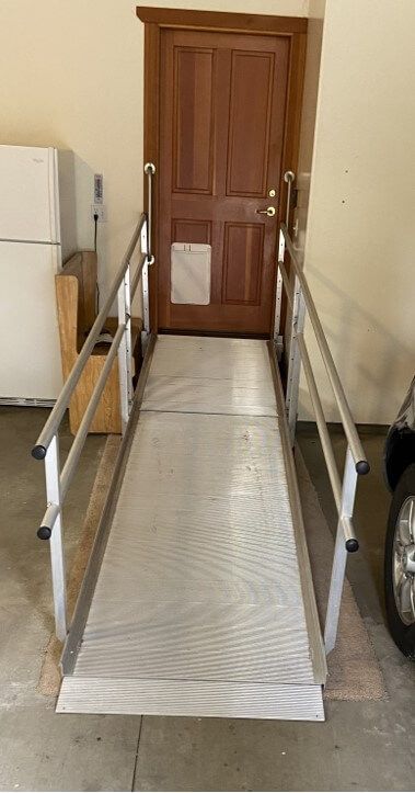 A wheelchair ramp leading to a door in a garage.