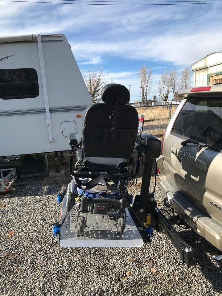 A mobility chair is attached to the back of a car.