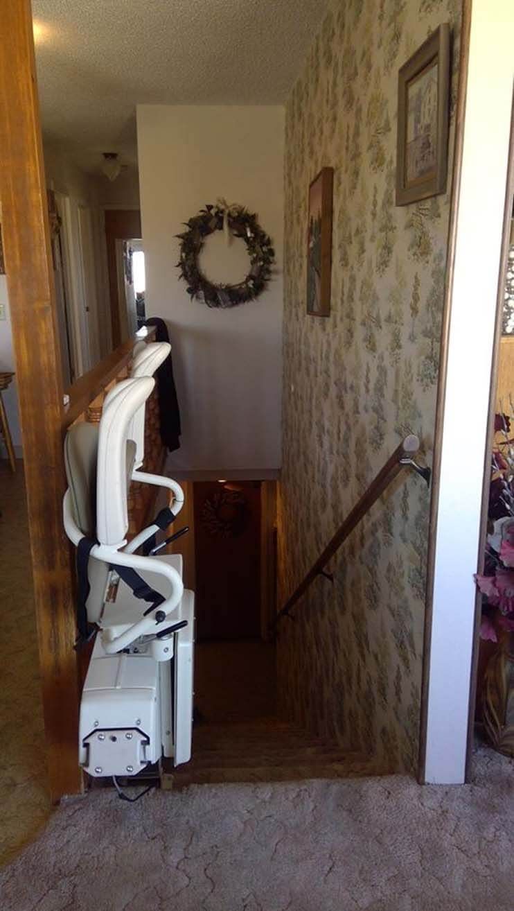 A stair lift is sitting in a hallway next to a staircase.