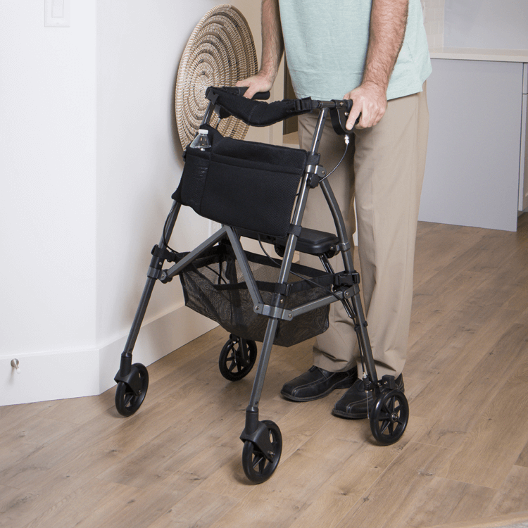 A man standing next to a walker on a wooden floor