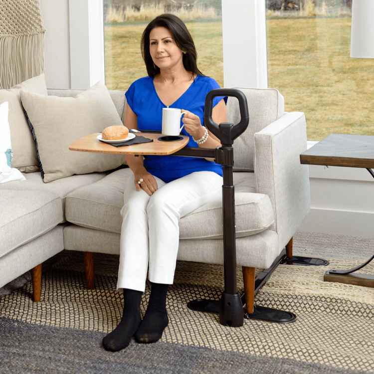 A woman is sitting on a couch holding a cup of coffee and a tray.