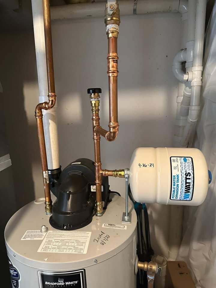 Water heater with copper pipes and a small expansion tank in a utility closet