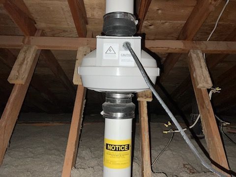A White Pipe With a Notice Sticker on It is Sitting Under a Wooden Ceiling