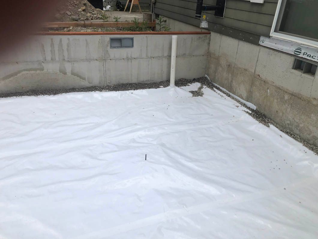 A White Tarp is Laying on the Ground Next to a Concrete Wall