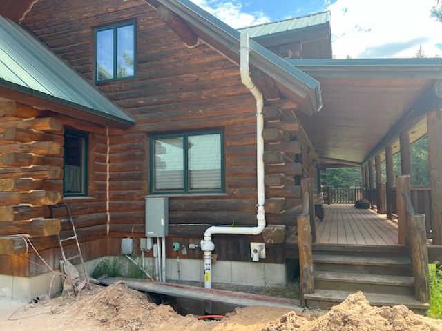A Log Cabin With a White Pipe on the Side of It