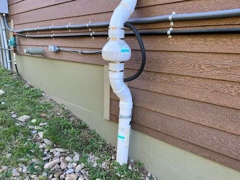 A white pipe is attached to the side of a house.