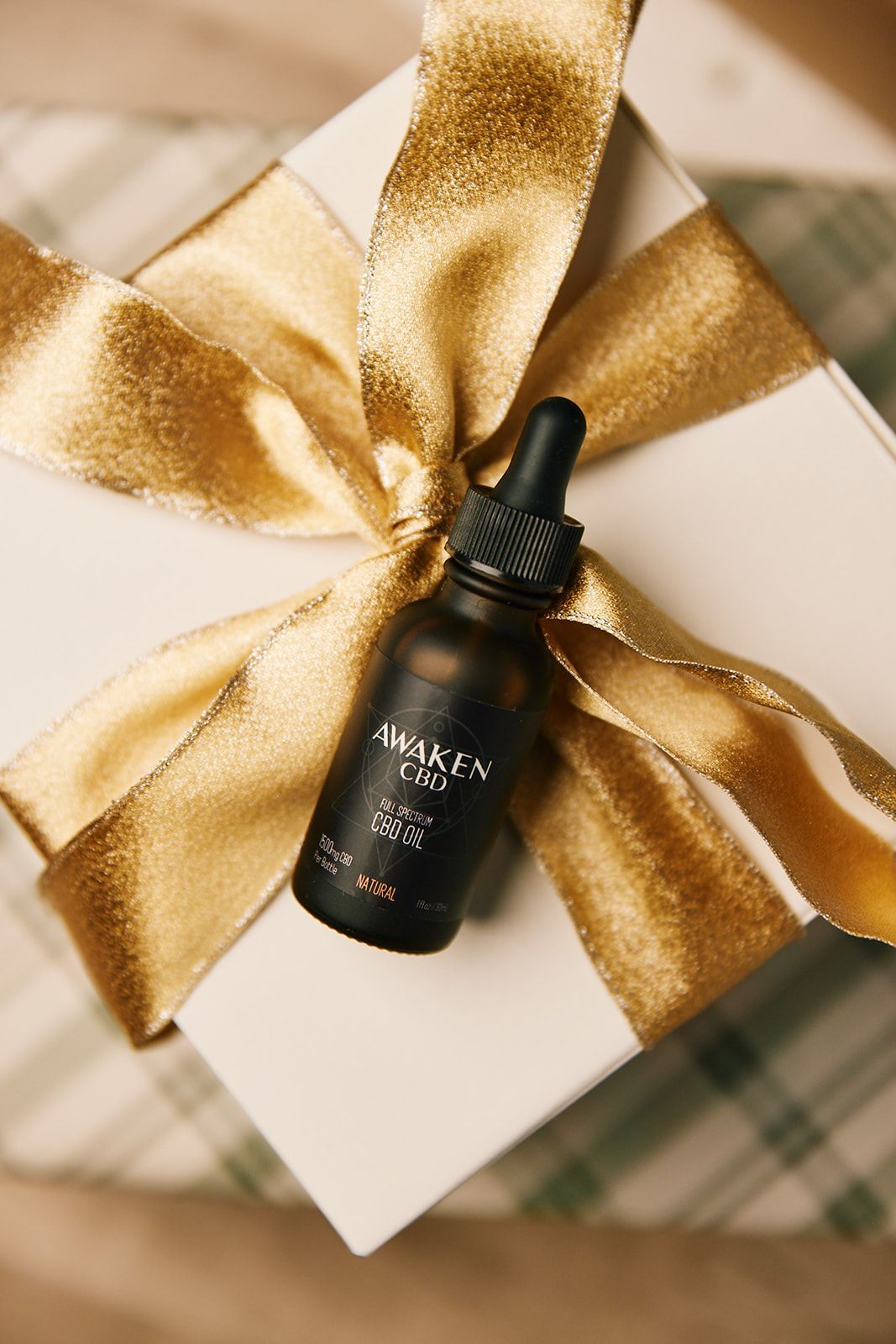 Awaken CBD Tincture laying on a Christmas bow
